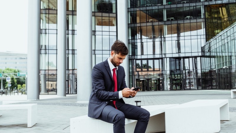 man using phone outside a business building